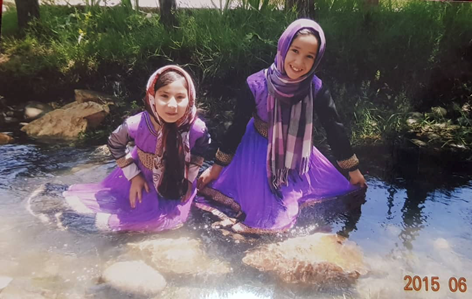 A photo of Marzia and Hajar Mohammadi as children sitting on the floor.