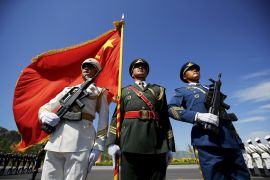 Officers and soldiers of China&#39;s People&#39;s Liberation Army hold a flag and weapons during a training session [File: Damir Sagolj/Reuters]