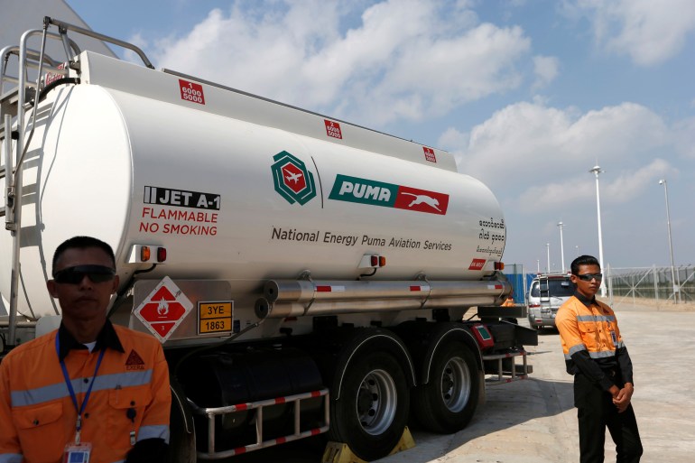 A jet fuel tanker at the Thilawa port. There are two port workers standing in front of it. There is a Puma logo on the side of the tanker and the words JET A-1
