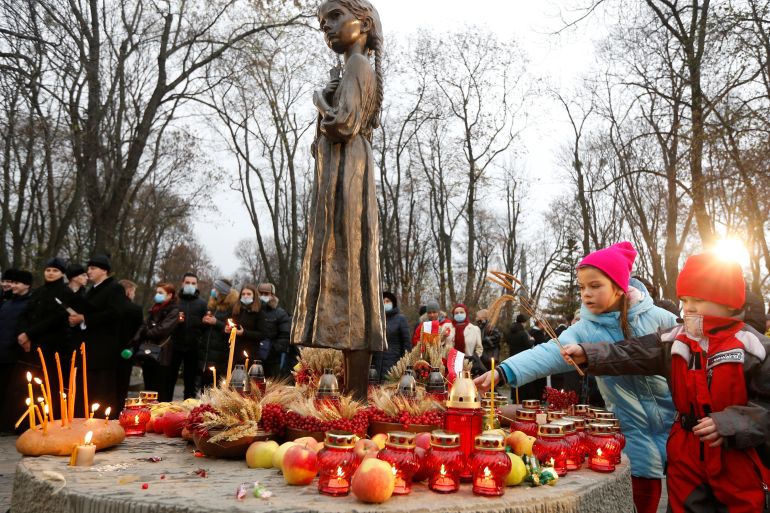 Children place ears of wheat as they visit a monument to Holodomor victims during a commemoration ceremony marking the 87th anniversary of the famine of 1932-33, in which millions died of hunger, in Kyiv, Ukraine, November 28, 2020.