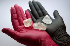 An employee shows gem-quality stones, including a rare 242-carat rough diamond that offered at an auction of Russian state-controlled diamond producer Alrosa [File: Tatyana Makeyeva/Reuters]