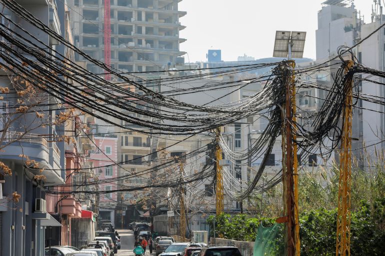 People walk near electricity cables attached to utility poles in Beiru