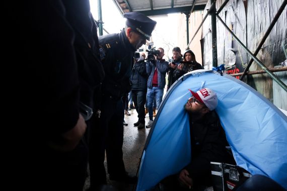 New York City Police Department (NYPD) officers speak to a resident of an encampment of homeless people in his tent.