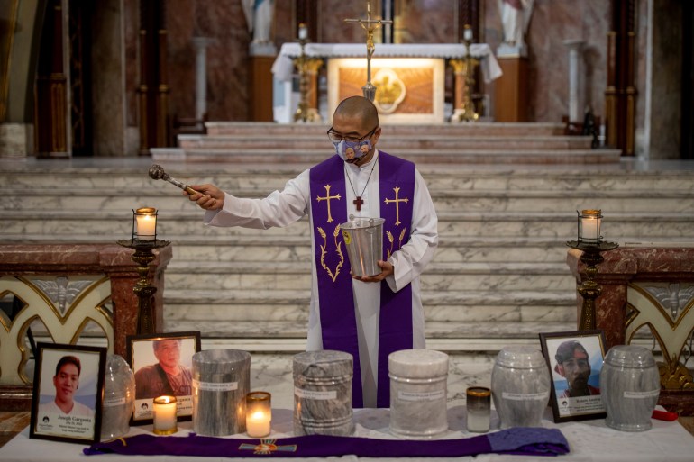 A priest blessing the urns of victims of the drug war in a Manila church.