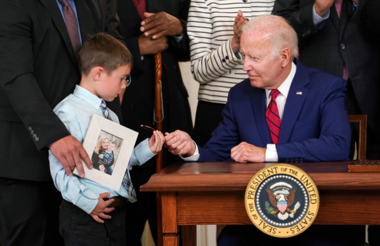 A young boy receives a pen from US President Joe Biden