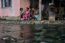 Village children pass the time in front of a home next to a flooding sea wall at high tide in Serua Village, Fiji, in 2022. As the community runs out of ways to adapt to the rising Pacific Ocean, the 80 villagers face the painful decision on whether to move or stay in their threatened homes [File: Loren Elliott/Reuters]