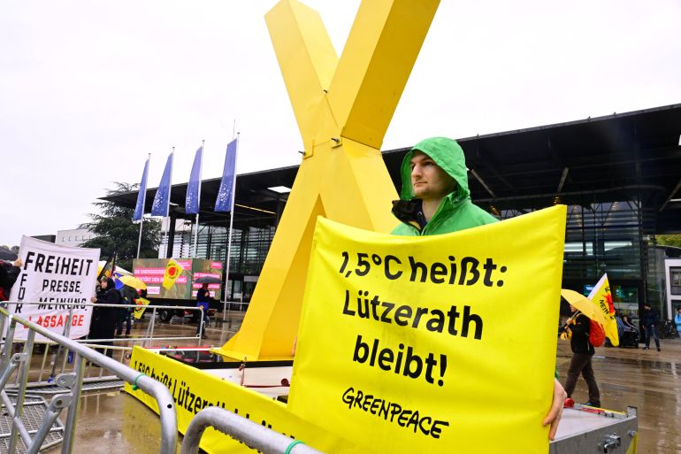 A demonstrator holds a banner in protest against climate change and for the preservation of the village of Lutzerath, in front of the Federal Convention of Germany's Greens party in Bonn, Germany, October 14, 2022. REUTERS/Benjamin Westhoff