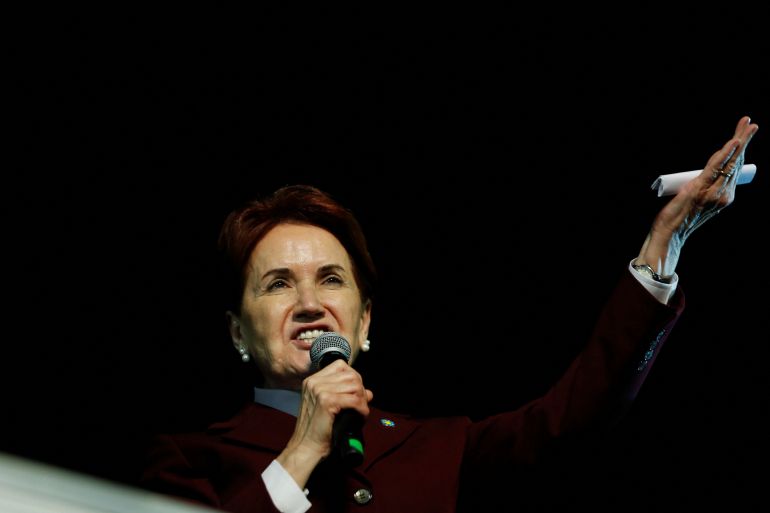 Meral Aksener speaks into a microphone with her left hand raised