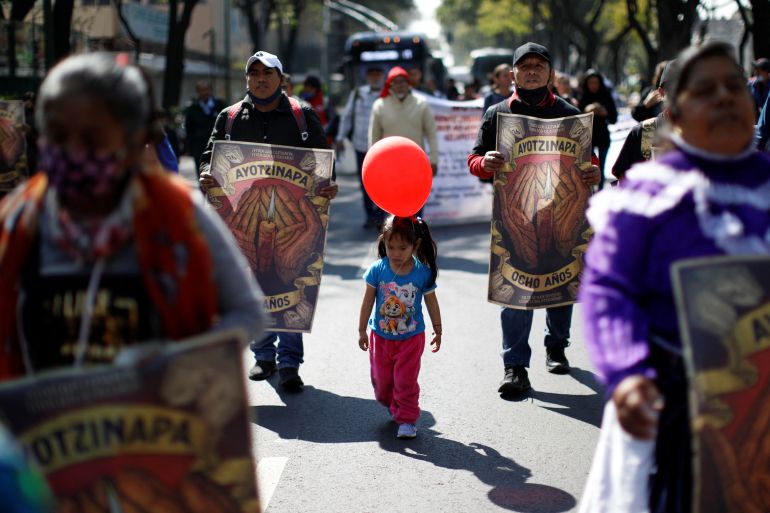 A girl holding a red balloon joins a march for the missing 43 students