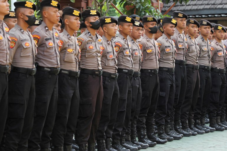 A row of police officers at a briefing ceremony. They are wearing pale brown shirts, black trousers and berets.