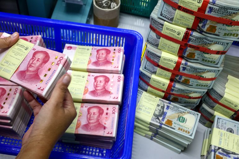 Un empleado del banco cuenta los billetes de renminbi (RMB) o yuan de China junto a los billetes en dólares estadounidenses en un Kasikornbank en Bangkok, Tailandia, el 26 de enero de 2023. REUTERS/Athit Perawongmetha