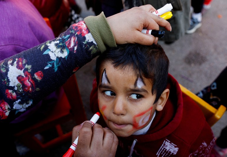 A woman paints a child's face during an activity to entertain and support mental health of children affected by the deadly earthquake in Osmaniye