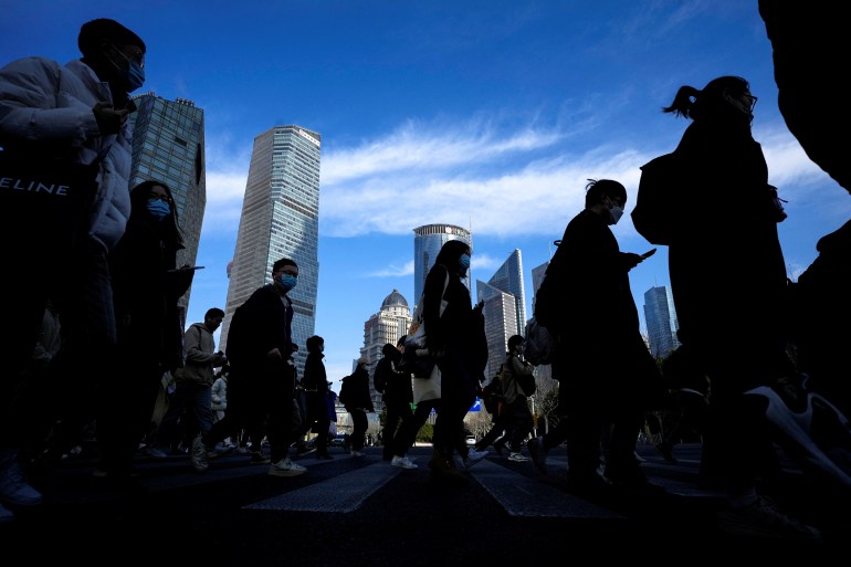 People silhouetted against a blue sky and skyscrapers as they walk in Beijing.