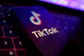 A picture showing a phone with the logo of the TikTok app on a laptop keyboard