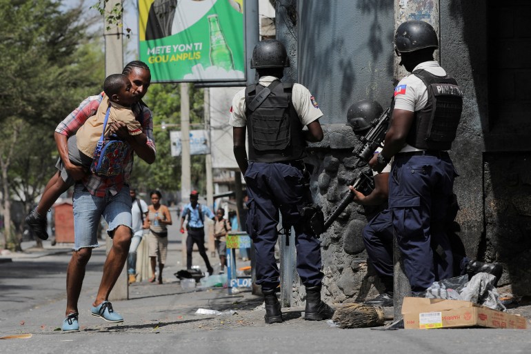 A man carries his son as they look for cover amid violence in Port-au-Prince, Haiti