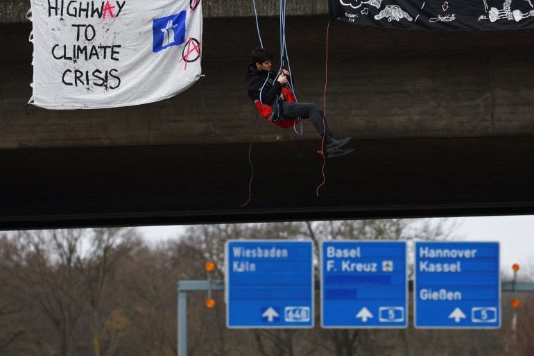A climate change activist hangs from a bridge during a protest against the traffic policy of the German government, at highway A 648 in Frankfurt, Germany