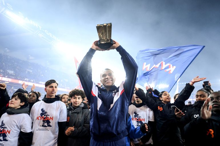 Paris St Germain's Kylian Mbappe celebrates with a trophy during the ceremony