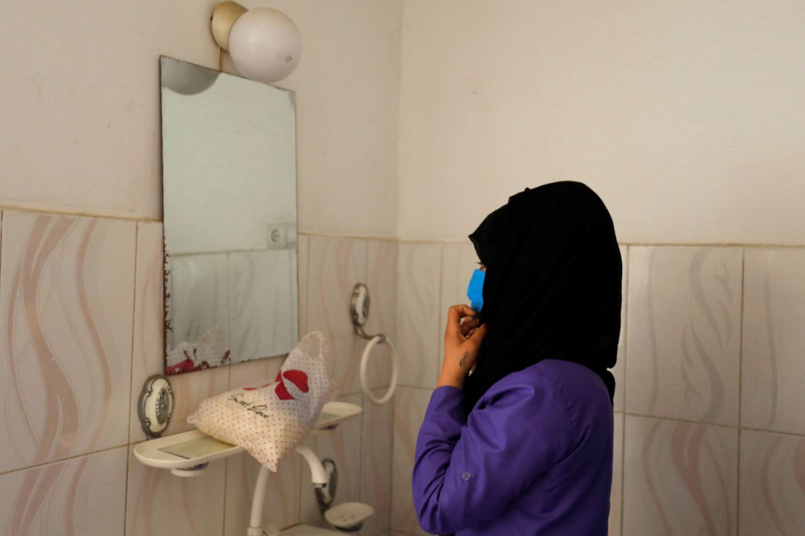 A trainee midwife arranges her headscarf in front of a mirror, in a training center in Bamiyan, Afghanistan