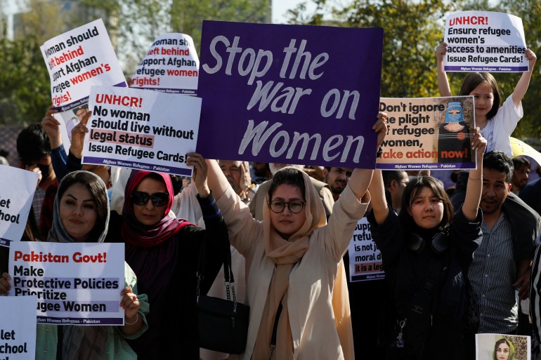 Afghan refugee women carry signs as they participate in the Women's March in Islamabad.