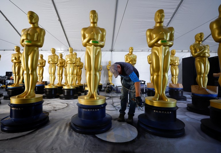 A worker puts the final touches at an Oscar statue before being placed out for display