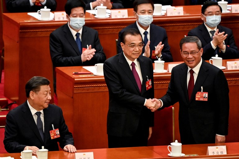 China's former Premier Li Keqiang shakes hands with newly elected Premier Li Qiang as China's President Xi Jinping looks on during the fourth plenary session of the National People's Congress (NPC) at the Great Hall of the People in Beijing, China on March 11, 2023. GREG BAKER/Pool via REUTERS