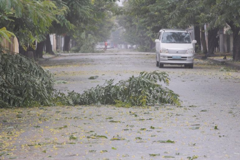 Fallen branches are seen on a street with a car not far off in the distance, as Cyclone Freddy is due to hit Mozambique again, in Quelimane, Zambezia.