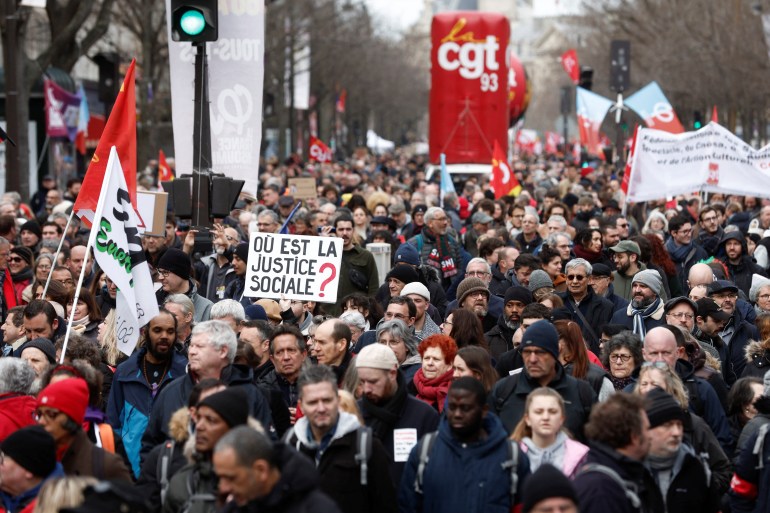The logo of the CGT trade union is seen behind hundreds of protesters in Paris, France.  A sign, written in French and on the front, reads, 