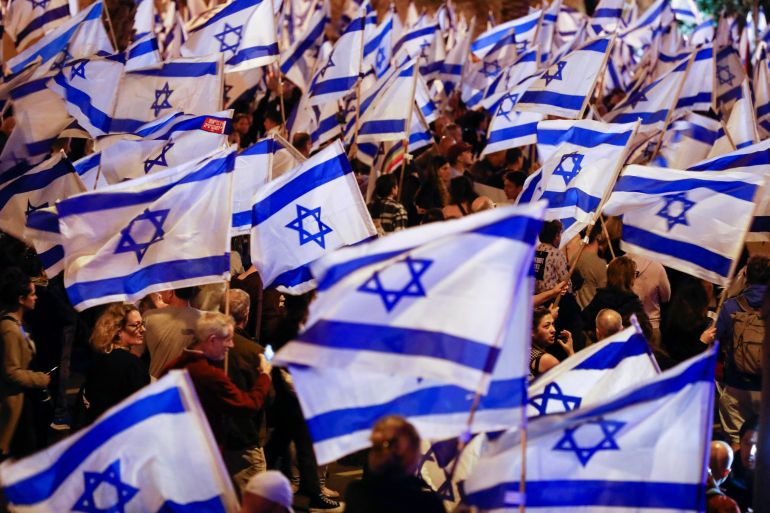 People hold Israeli flags during a demonstration in Tel Aviv, Israel.