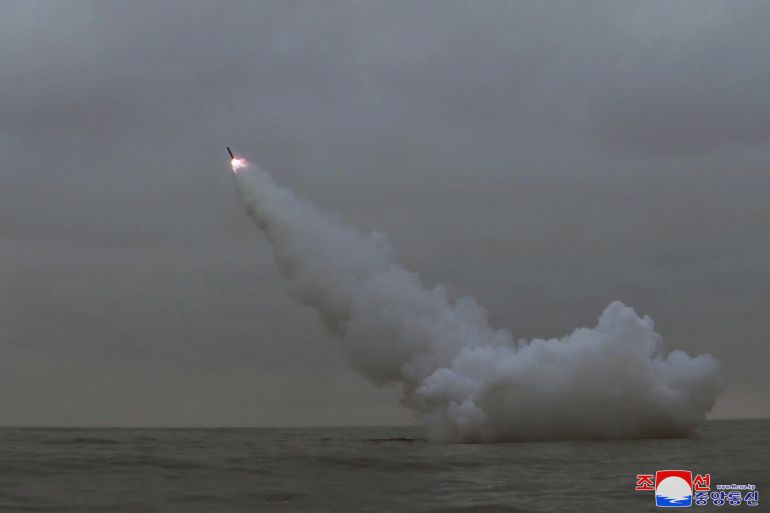 A weapon soaring into the air from the sea. Flames are visible at the tip and there is trail of white smoke clouds.