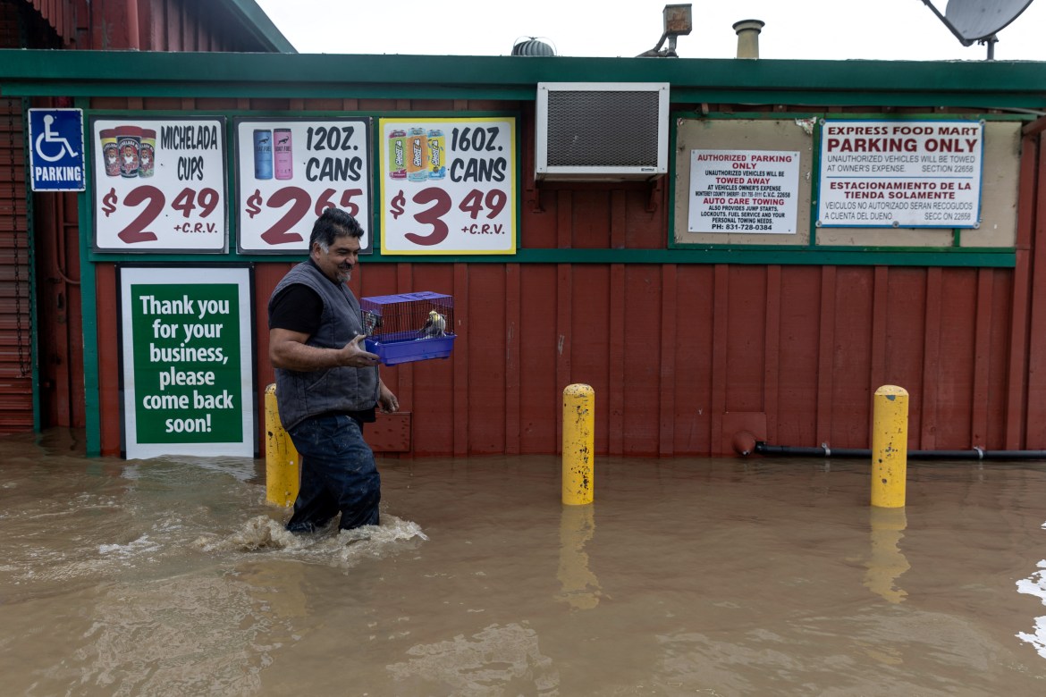 A local resident walks through a flooded area as he rescues his birds in Pajaro, California