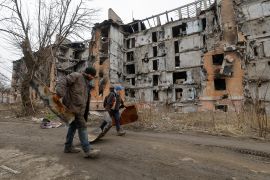 Local residents walk past a multi-storey apartment block, which was destroyed in the course of Russia-Ukraine conflict, in Mariupol, Russian-controlled Ukraine, March 16, 2023. REUTERS/Alexander Ermochenko