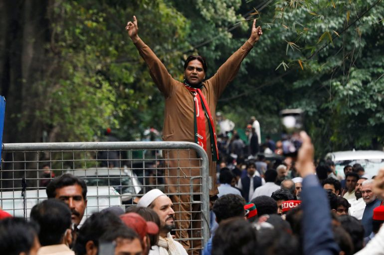 Um apoiador do ex-primeiro-ministro paquistanês Imran Khan gesticula enquanto outros se reúnem do lado de fora da casa de Khan, em Lahore
