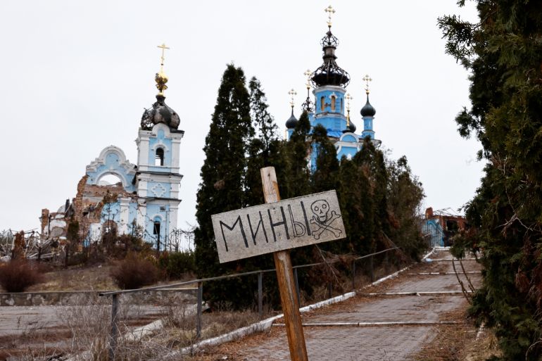 A sign warning about mines in front of a war-damaged Orthodox Church in Donetsk, Ukraine.