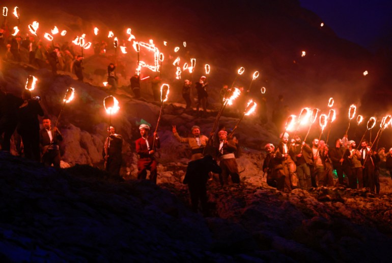 Curdos iraquianos carregam tochas de fogo enquanto celebram o Nowruz Day, um festival que marca o primeiro dia da primavera e o Ano Novo persa, na cidade de Akra, perto de Duhok