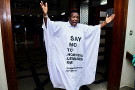 Member of Parliament from the Bubulo contituency John Musira dressed in an antigay gown gestures as he leaves the chambers during the debate of the Anti-Homosexuality bill, which proposes tough new penalties for same-sex relations during a sitting at the parliament buildings in Kampala, Uganda.