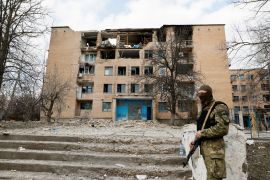 A security personnel stands guard at a site of a building heavily damaged by Russian drone strikes, in the town of Rzhyshchiv, in Kyiv region, Ukraine [Alina Yarysh/Reuters]