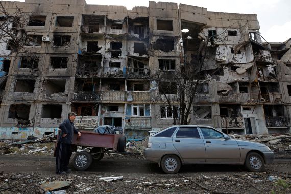 A resident stands next to a car in front of a residential building heavily damaged in the course of Russia's war in the settlement of Toshkivka, Luhansk region, Russian-controlled Ukraine.