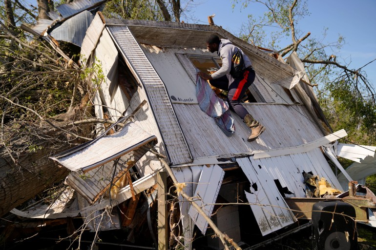 Jeremiah Stapleton, 18, climbs into the window of his grandfather's home, which was crushed in a massive storm in Mississippi