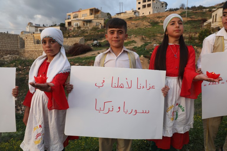 A boy holds a sign that reads 'Our condolences to our family in Syria and Turkey'