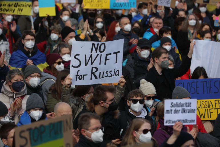 A protester holds a placard reading "No SWIFT for Russia" during a rally against Russia's invasion of Ukraine on February 26, 2022, in Frankfurt am Main, western Germany. (Photo by Yann Schreiber / AFP)