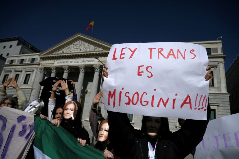 Protesters holding sign reading 'The trans law is misogynist' demonstrate against a trans rights law in front of the Spanish Congress, in Madrid on February 16, 2023. - As Spain prepares to adopt a law simplifying the process for self-identifying as transgender, other early adopters are applying the brakes over the complexities involved in this highly sensitive issue. The law is set to be passed on February 16, 2023, to approve a transgender rights bill letting anyone 16 and over change gender on their ID card. That will make it one of the few nations to allow it with a simple declaration. (Photo by OSCAR DEL POZO / AFP)
