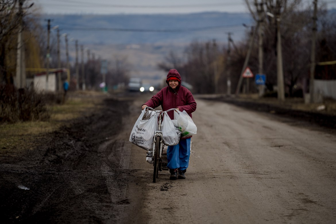 A woman pushes a bicycle down a street in Konstantinovka, Donetsk region
