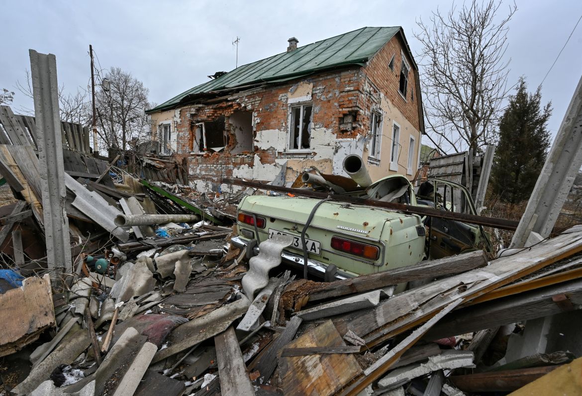 This photograph shows a destroyed car and a heavily damaged house in the village of Tsupivka, Kharkiv region