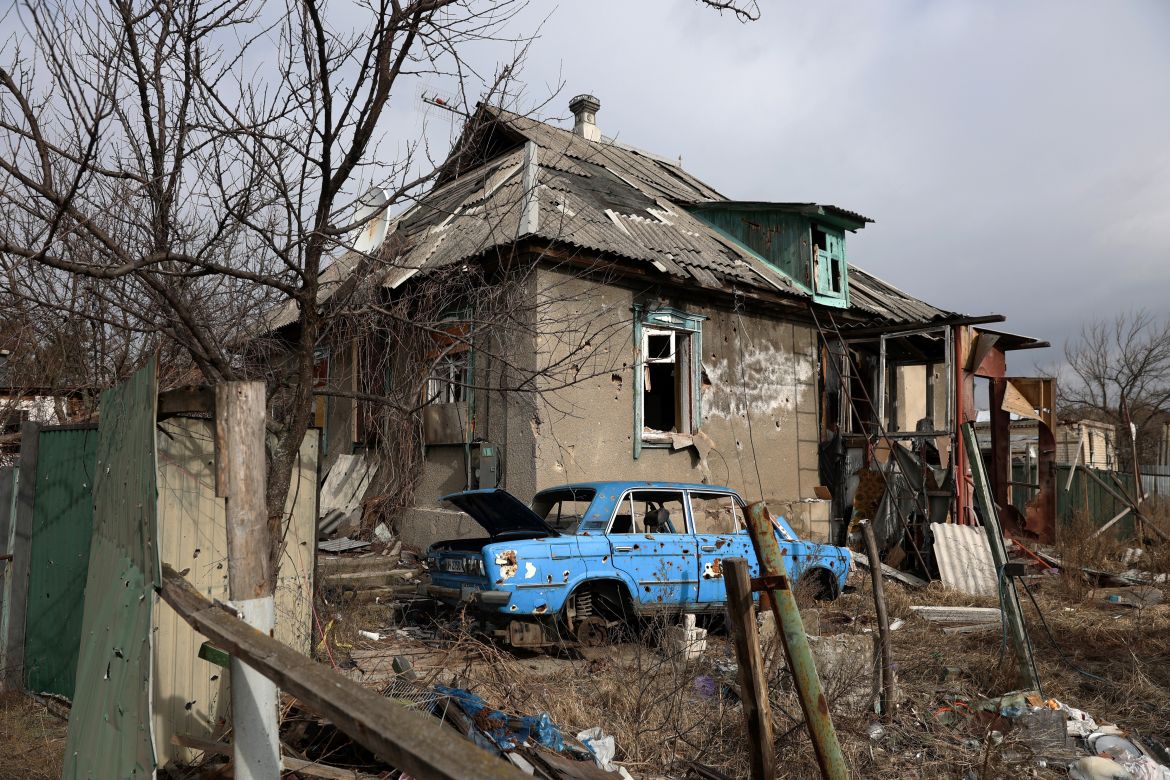 This photograph shows a destroyed car and a heavily damaged house in the town of Svyatogirsk, Donetsk region