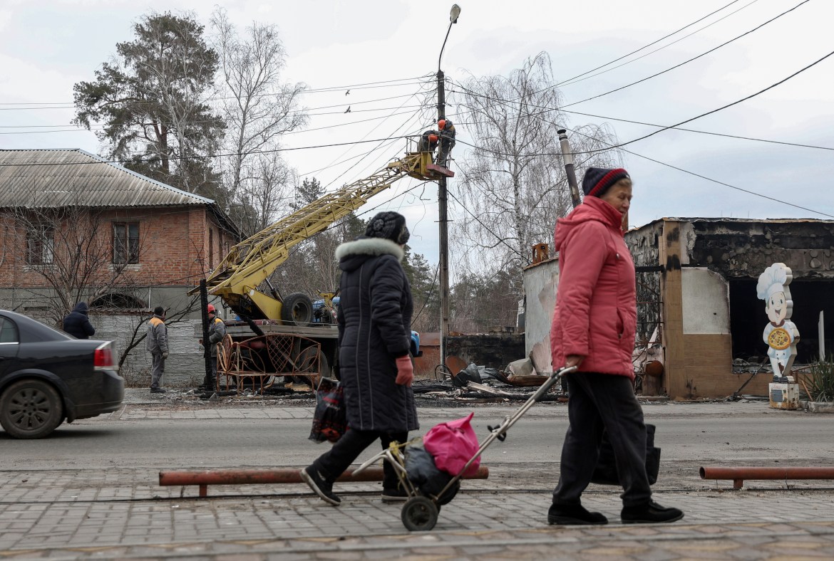 Local residents walk on a street as employees work on electricity cables in the town of Svyatogirsk, Donetsk region