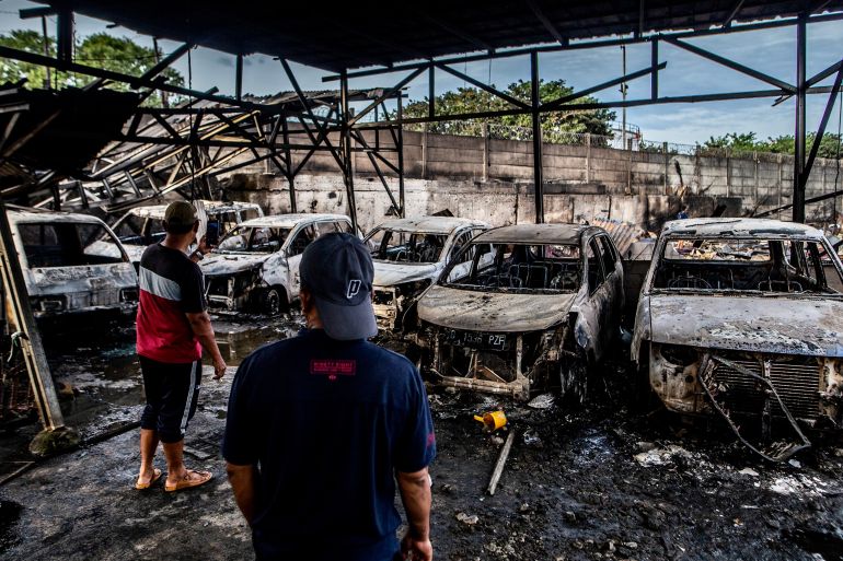 Two men look at burnt cars in Plumpang, north Jakarta on March 4, 2023, after a fire at a nearby state-run fuel storage depot run by energy firm Pertamina. (Photo by ADITYA AJI / AFP)
