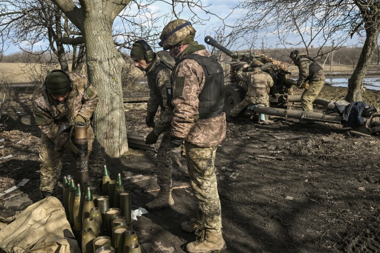 Ukrainian servicemen prepare munitions to fire with a 105mm Howitzer towards Russian positions