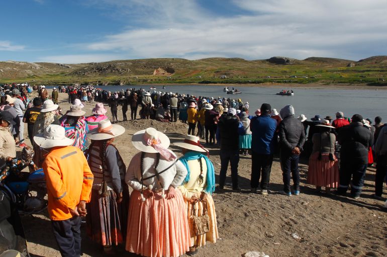 People gather at the site where rescue teams attempted to recover the bodies of five Peruvian soldiers that drowned after jumping into the freezing waters of the river Ilave