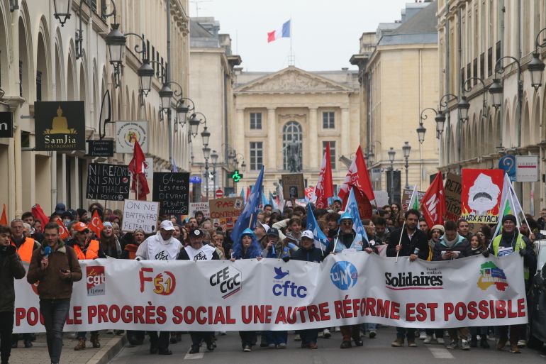 Protesters hold a banner representing different unions as the participate in a demonstration near the Place Royal in Reims, France