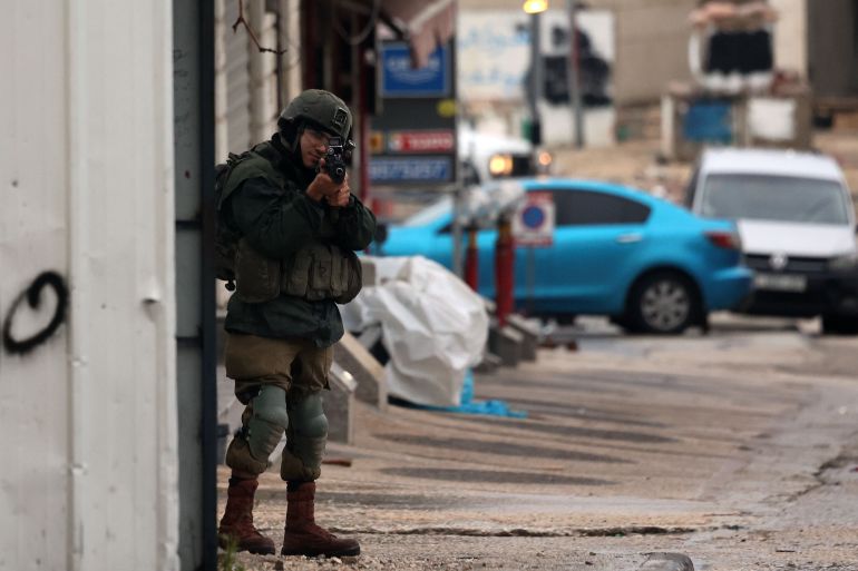 An Israeli soldier aims his weapon in the Palestinian town of Huwara